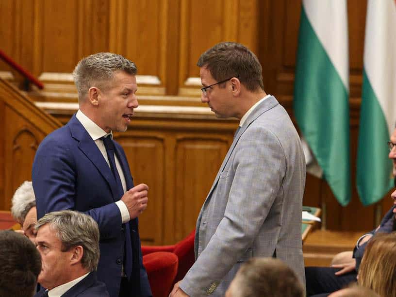 Politikai beszélgetés két férfi között egy tanácsteremben.